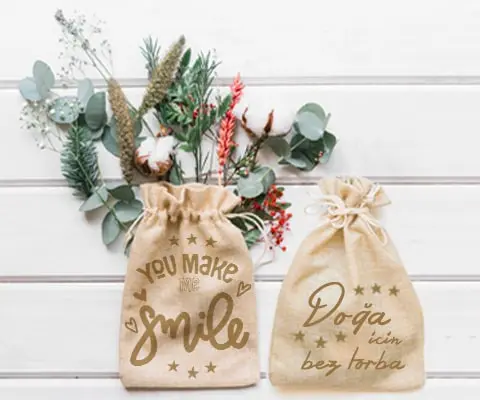 Dikişli ve büzgülü bez keseler, yüksek kaliteli ham bezden üretilmiş, promosyon ürünleri olarak kullanılabilir. Sol kesede yeşil yapraklar ve çiçekler var, "You make smile" yazılı, sağdaki ise "Doğa için bez torba" yazılı.